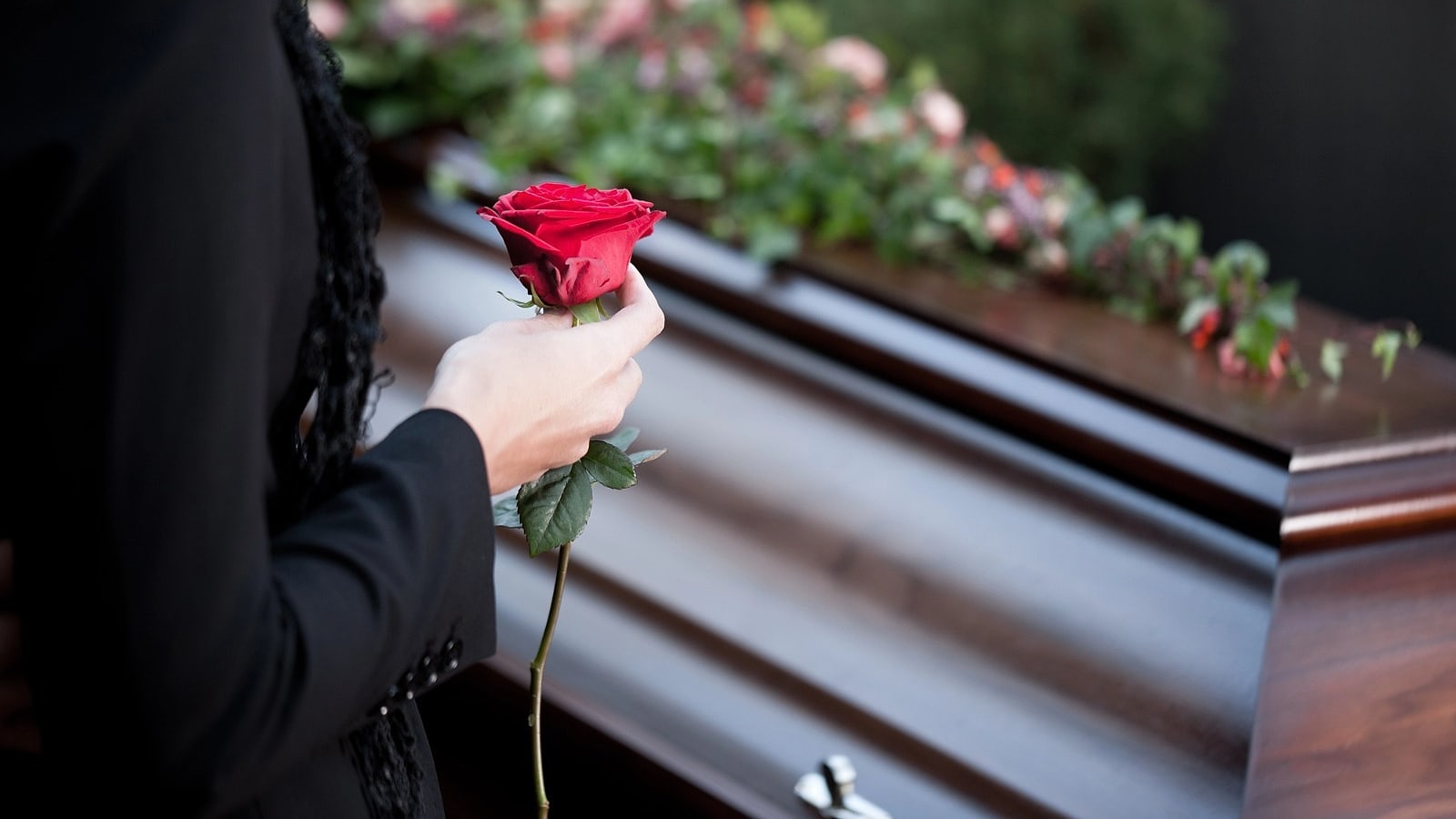 Una donna posa una rosa rossa sul feretro durante il commiato