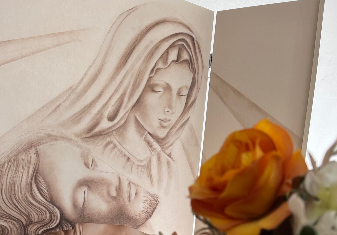 Il bassorilievo della Pietà con rose arancioni in primo piano
